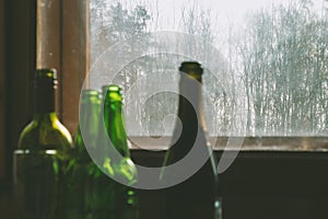 Several empty bottles of alcohol near the dirty window. Selective focus. Alcoholism, drunkenness, loneliness and depression