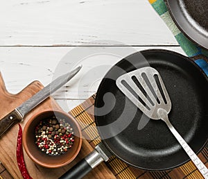 Several empty cast-iron frying pans on a white wooden background. mix peppers in bowl.