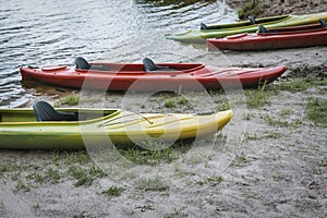 Several empty colorful kayaks on the beach