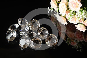 Several excellent pure diamonds and bouquet of tea roses with reflection on black mirror background close up view. Jewelry