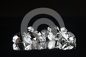 Several excellent pure diamonds with reflection on black mirror background close up view selective focus. Jewelry diamonds sale,