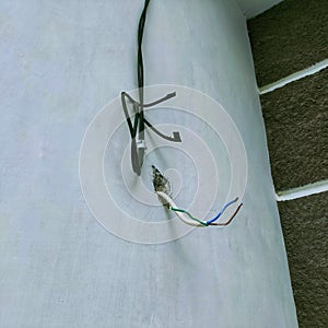 Several exposed electrical copper wires protruding from a whitewall.