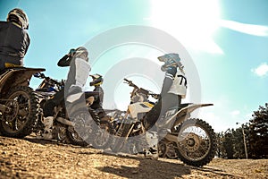 Several extreme motorcyclists are preparing for off-road driving, rear view against a blue sky. Extreme concept, moto