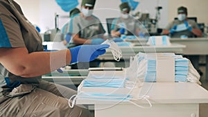 Several factory workers stretching and packing face masks at a medical mask manufacturing facility