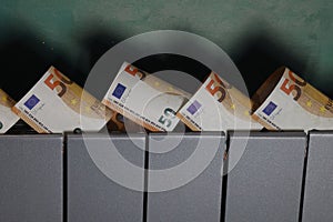 Several fifty euro banknotes inserted into the slots of the heating radiator, rising heat costs, fuel crisis in Europe