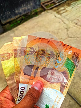 Several five thousand rupiah notes in hand