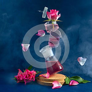 Several flasks are in the air. Levitation. Pink roses and flying petals. Mystical picture. Blue background, smoke