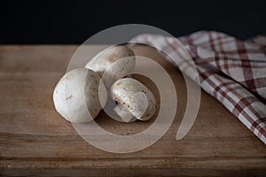 Several fresh champignons laying on wooden cutting board
