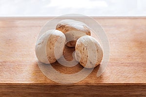 Several fresh champignons laying on wooden cutting board