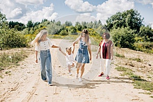 Several generations of women of the same family are walking along a dirt road outside the city, enjoying the time spent