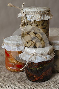 Several glass jars with canned mushrooms and sun-dried tomatoes