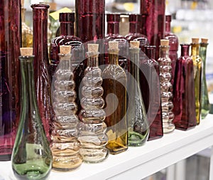 Several glass transparent bottles with cork stopper on a store shelf. Transparent glass bottles on a white shelf. Vintage glass