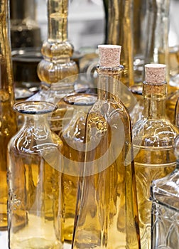 Several glass transparent bottles with cork stopper on a store shelf. Transparent glass bottles on a white shelf. Vintage glass