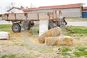 Several hay bales next to the tractor trailer and country houses