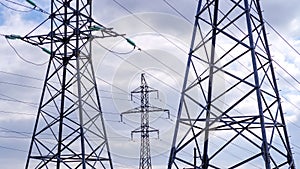 Several high-voltage towers against a cloudy sky. Power lines. Concept of communication and transmission of electricity.