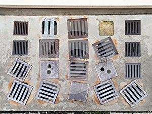 Several iron exhaust grills are placed in a row on the sidewalk