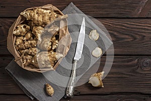 Several Jerusalem artichoke tubers in a paper bag on a wooden table with copy space. Helianthus tuberosus. Top view