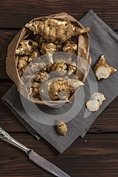 Several Jerusalem artichoke tubers in a paper bag on a wooden table with copy space. Helianthus tuberosus. Top view