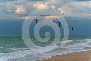 Several kite-surfers fighting with gusty windy weather and waves in the ocean. Amazing adventure and adrenaline sport