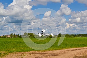 Several large satellite communication antennas in a field against a blue sky. Space Communication Center