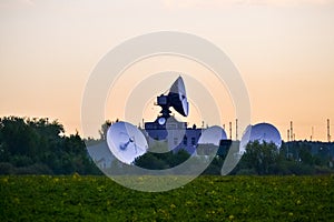 Several large satellite communications antennas in the field in the early morning. Space Communication Center