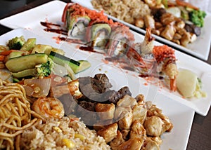 Several long white plates covered with assortment of sushi options for diners in restaurant