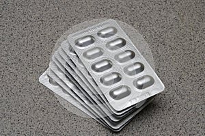 Several many medication pills in reflective opaque silver packaging