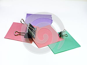 Several metal paper clips and multicolored paper stickers on a white background, black and one green paper clip