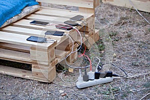 Several mobile phones charging at wooden pallet