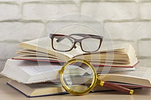 Several open books,glasses, and a magnifying glass on the table