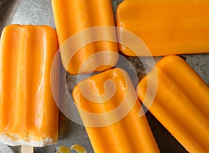 Several orange creamsicles on a galvanized steel plate. Close up view.