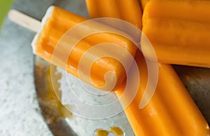 Several orange creamsicles on a galvanized steel plate. Close up view.