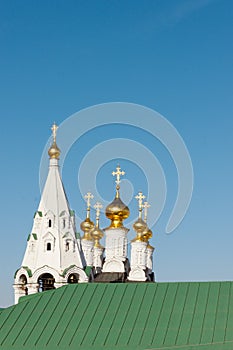 Several orthodox bright shiny crosses are on top of the golden cupolas of stone white old church. A green roof is on the bottom of