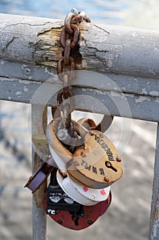 Several padlocks are chained to the railing of a small bridge, inscription in Cyrillic, you and me forever