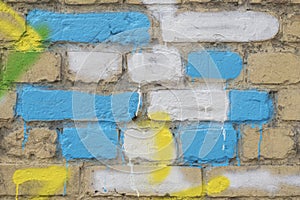 Several painted bricks in blue, yellow and white on an old dirty wall, as graffiti. Colorful grunge texture of wall