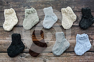 Several pairs of handmade baby socks on wooden background