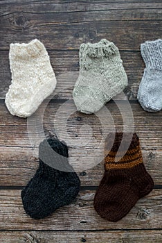 Several pairs of handmade baby socks on wooden background