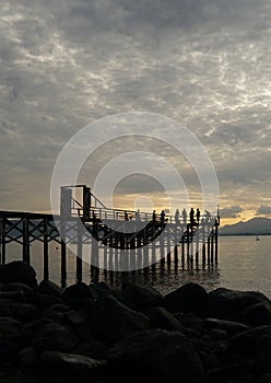 Several people gathered on the wooden pier while waiting for the sunrise.