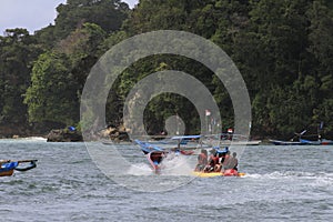 Several people are riding a banana boat on Pangandaran beach