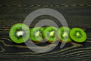 Several pieces bright juicy ripe beautiful kiwi on a coarse dark wooden background from boards
