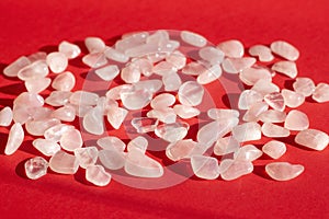 Several pieces of polished pink quartz on red background. Narrow focus line, shallow depth of field front view