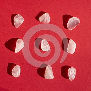 Several pieces of polished pink quartz on red background. Minimal color still life photography