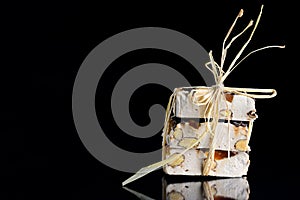 Several pieces of torrone or white nougat with nuts, candied fruits and chocolate are tied together with raffia and lie on a