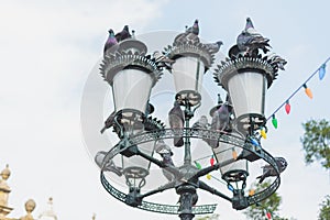 Several pigeons perched on a park luminary.