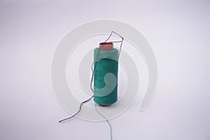 Several piles of sewing thread spools of various colors isolated on a white background and also with small sewing needles stuck