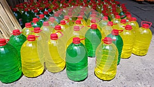Several plastic gallons with red lid. many plastic gallons of colored liquid. wholesale gallon warehouse