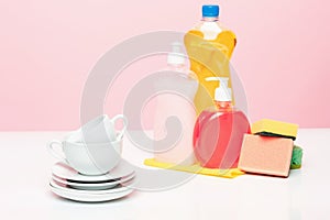 Several plates, a kitchen sponges and a plastic bottles with natural dishwashing liquid soap in use for hand dishwashing
