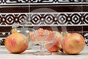 Several pomegranates around a crystal goblet full of white grains