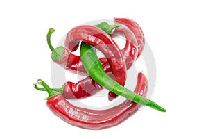 Several red and one green chili peppers on light background