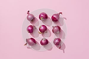 Several red onions on a pink background.